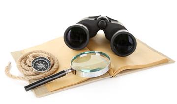 Binoculars Magnifying glass rope and compass on book