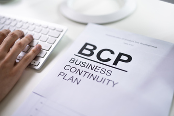 Business Continuity Plan BCP book with hand and computer keyboard Business Continuity Plan BCP book with hand and computer keyboard