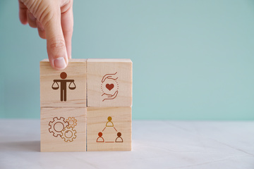 Hand holding wooden blocks with Ethic icons, business corporate regulation standards, target, justice compliance concept