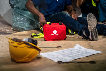Worker on ground from fall with first aid kit