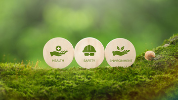 Green grassy background with health safety and environment coins