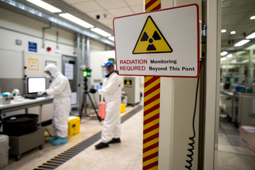 A laboratory scene showing workers in protective gear near a radiation warning sign, highlighting safety protocols in a controlled environment